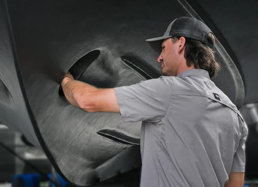Male marina worker servicing a boat.